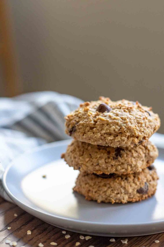 three sourdough oatmeal cookies stacked on a gray plate with a blue and white plaid towel layer on a table