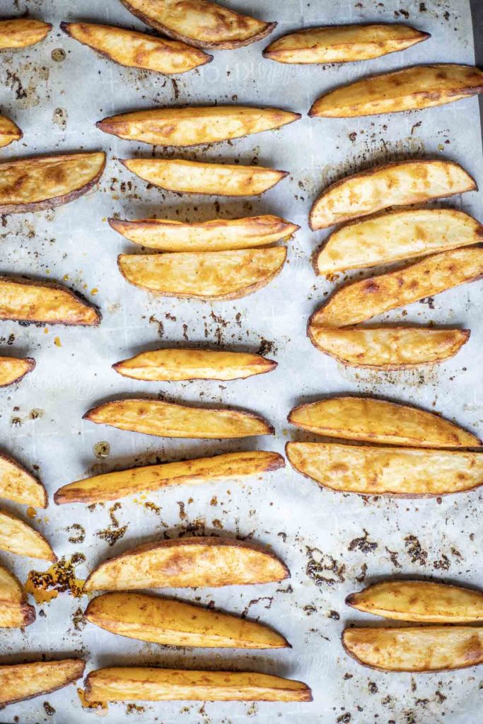 oven roasted potato wedges cooked on a sheet pan with parchment paper