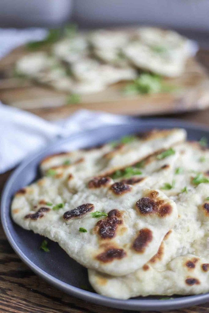 close up picture of sourdough flatbreads topped with herbs on a dark gray plate.