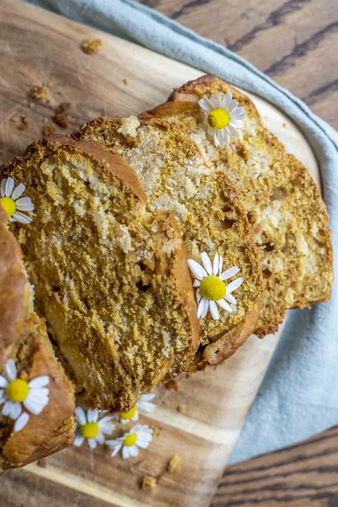 slices of pumpkin sourdough bread topped with chamomile flowers on a wood cutting board
